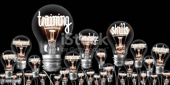 Photo of light bulbs with shining fibers in a shape of TRAINING, SKILLS and KNOWLEDGE concept related words isolated on black background